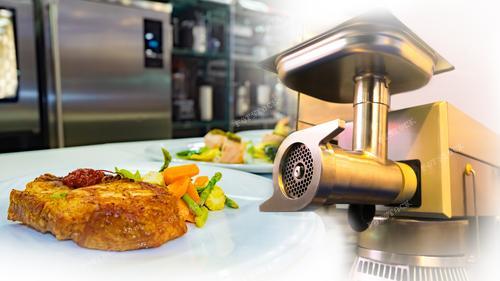 Фотография демонстрирует мясорубку рядом со свежеприготовленным стейком, предоставляя гармоничное сочетание кулинарного процесса и профессионального оборудования. Это изображение может эффективно использоваться в рекламе кухонного оборудования, ресторанных услуг и подготовке высококачественных блюд. Стейк, мясорубка и общая атмосфера кухни вызывают ассоциации с высоким кулинарным мастерством и вниманием к деталям. Фотография станет прекрасной иллюстрацией для кулинарных публикаций, ресторанных меню и материалов о процессе приготовления пищи.